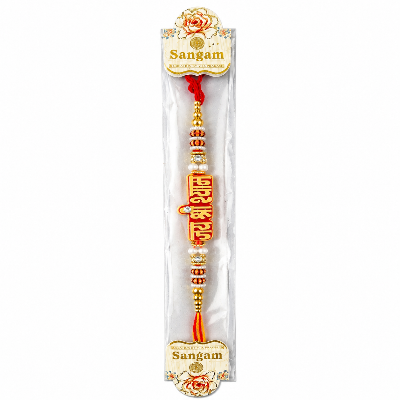 A packaged Sangam Rakhi with a red and gold central charm
