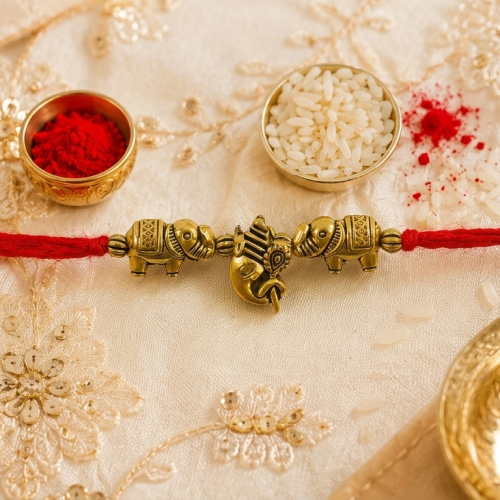 A traditional Indian Rakhi with a red cord and gold-plated elephant charms