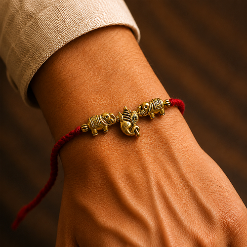 A close-up of a person's wrist wearing a red cord bracelet with two gold elephant charms