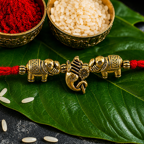 A brass Rakhi with elephant and Ganesha charms 