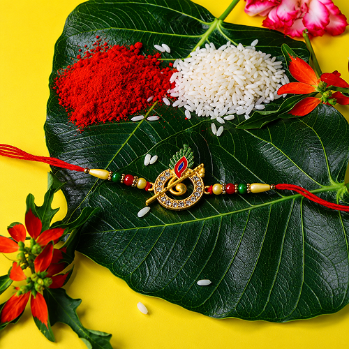 A decorative Rakhi with a gold-tone swastika symbol and red thread 