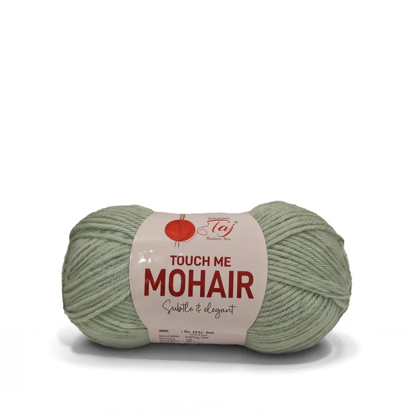 A skein of sage green mohair yarn with a paper label reading 'TOUCH ME MOHAIR'
