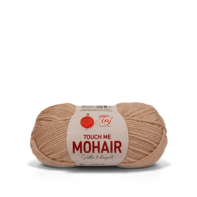 A skein of Tej Touch Me Mohair yarn in a soft, warm beige color, wrapped with a white paper label 