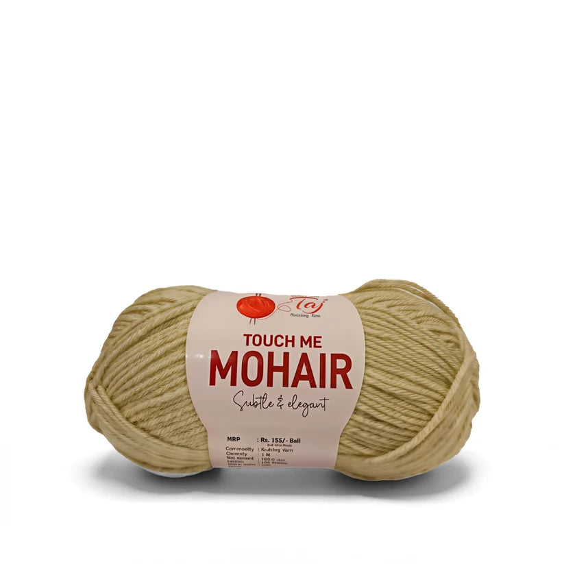 A ball of Touch Me Mohair yarn in a soft beige color, wrapped with a cream-colored paper
