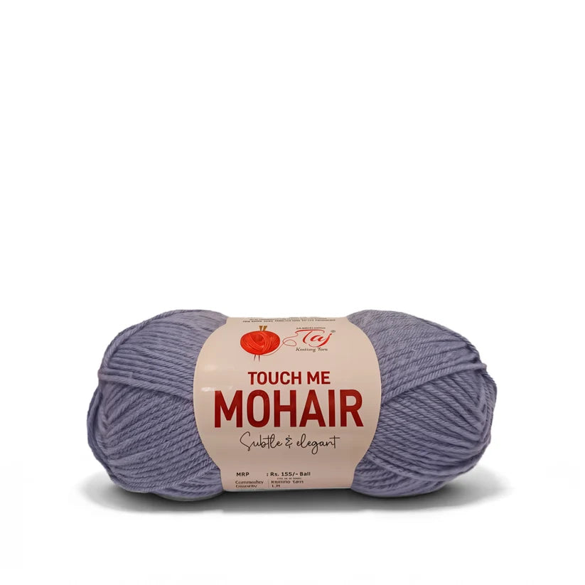 A skein of Touch Me Mohair yarn in a dusty lavender-purple color, wrapped with a cream-colored paper label