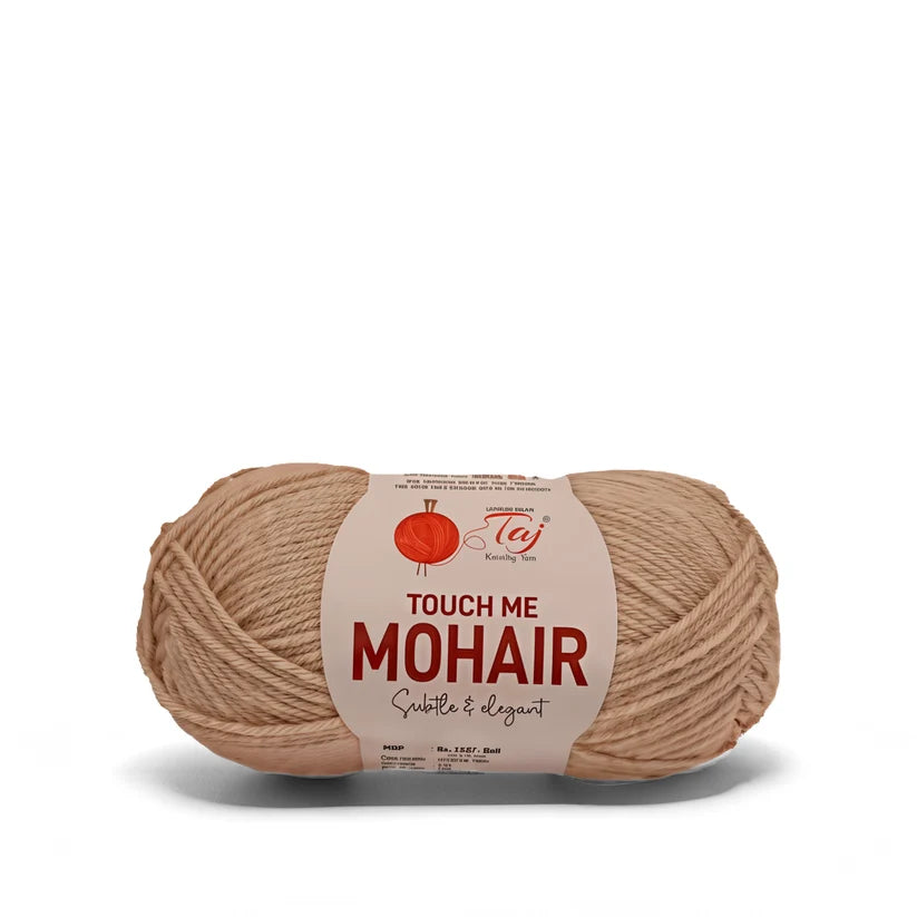 A single skein of Taj Touch Me Mohair yarn in a warm beige/tan color, featuring a white paper label