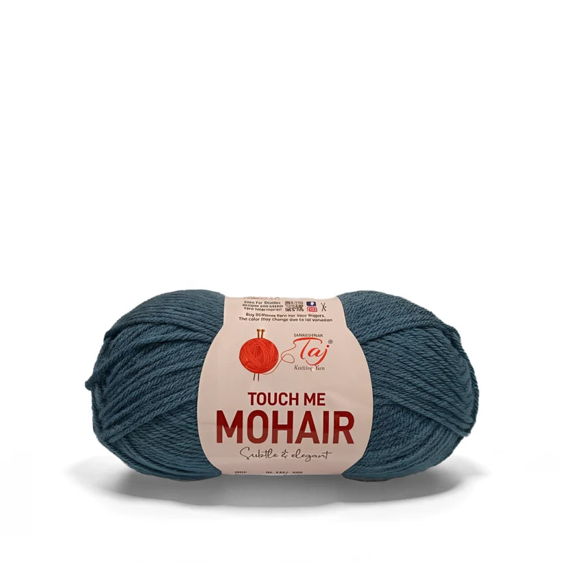 A skein of teal blue mohair yarn with a cream paper label that reads 'TOUCH ME MOHAIR'
