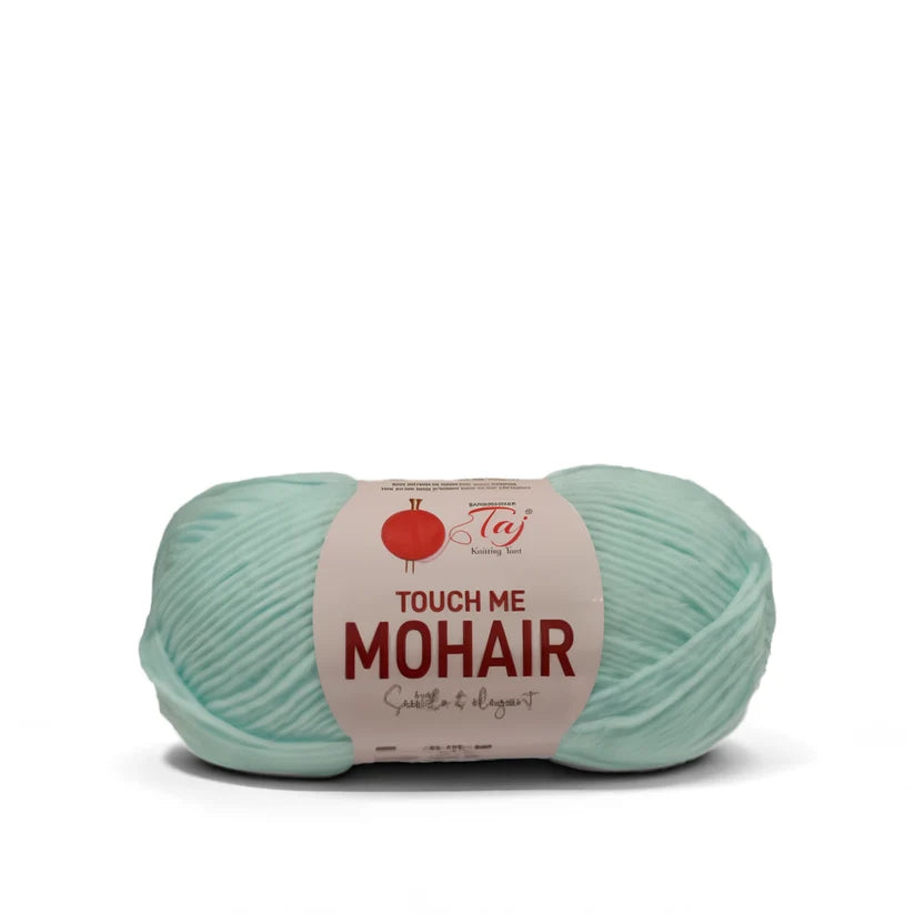 A single skein of fingering yarn in a pale mint green color, wrapped with a paper label that reads 'TOUCH ME MOHAIR'

