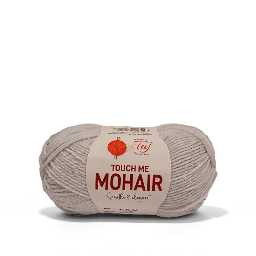 A single skein of Mohair yarn in a light taupe-beige color, wrapped with a paper label that reads 'TOUCH ME MOHAIR'